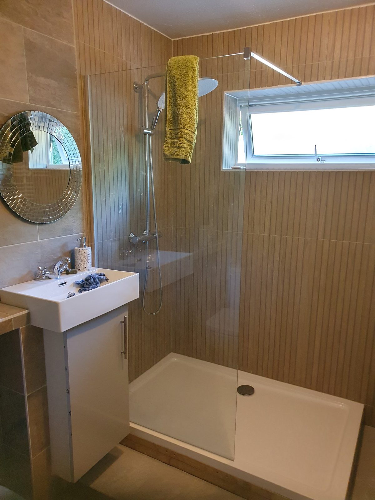 Finished shower room with a walk-in shower, glass screen and timber-effect wall panels