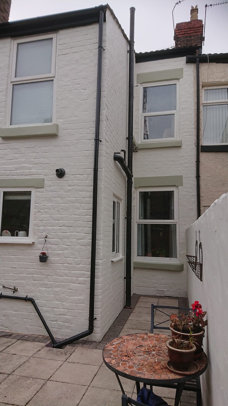 Rear of a terraced house with the brickwork painted white and new black downpipes