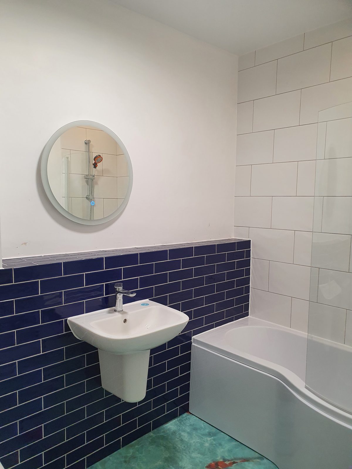 Bathroom with navy metro tiles, white wall tiles, a white basin and a curved bath
